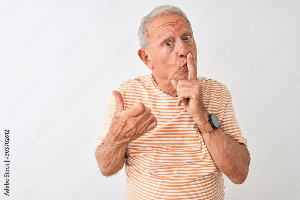 Senior grey-haired man wearing striped t-shirt standing over isolated white background asking to be quiet with finger on lips pointing with hand to the side. Silence and secret concept. Senior grey-haired man wearing striped t-shirt standing over isolated white background asking to be quiet with finger on lips pointing with hand to the side. Silence and secret concept.