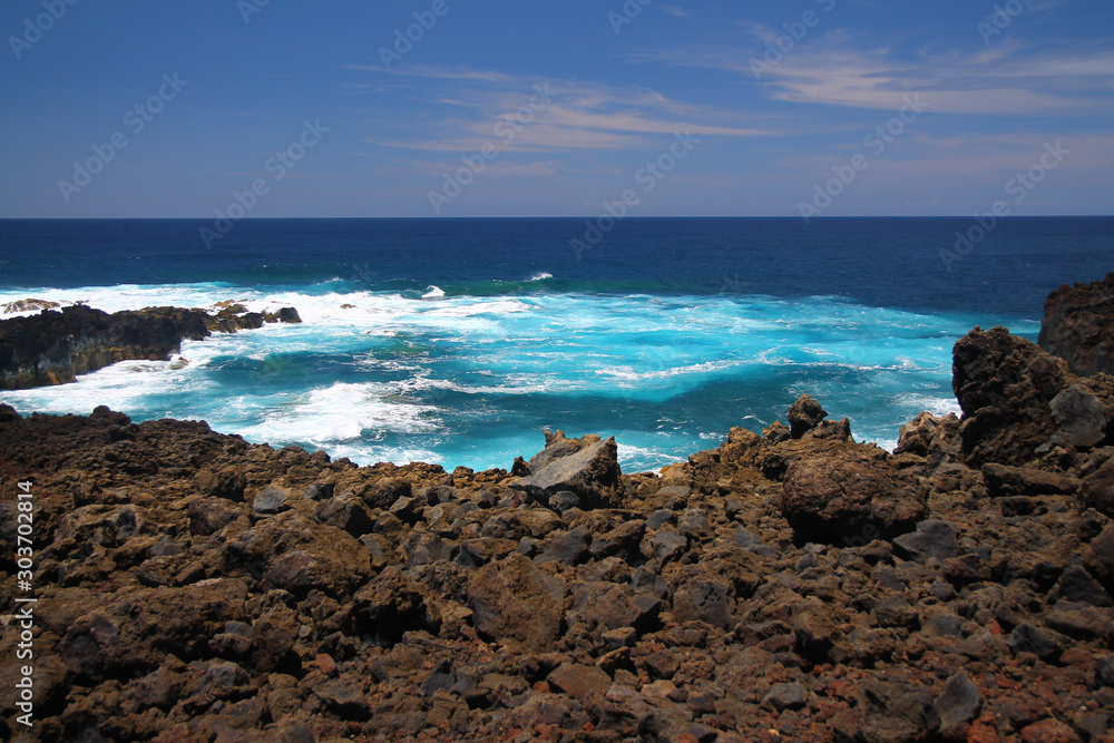 The intense blue sea and the black volcanic rocks