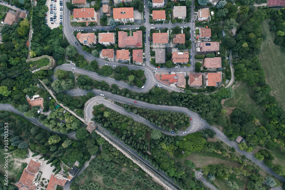 Overhead aerial drone shot of winding mountain road with streets to Castel San Pietro in Verona, Italy