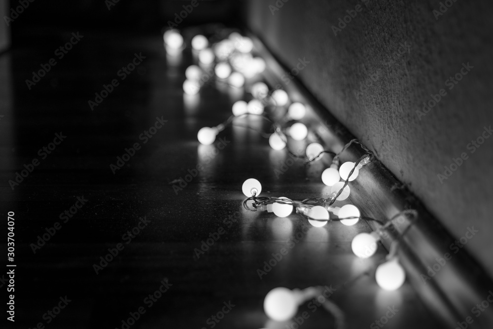 Φωτογραφία Black and white mood and tone of close up view of decorative wire led small warm white light bulbs lay on a floor at corner of dark and dim room