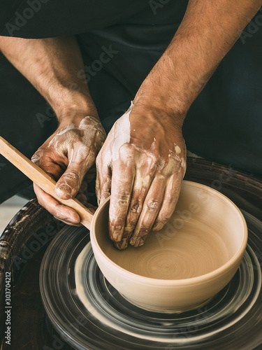 Ceramist at a pottery workshop Man is sculpting a bowl behind a rotating potter's wheel