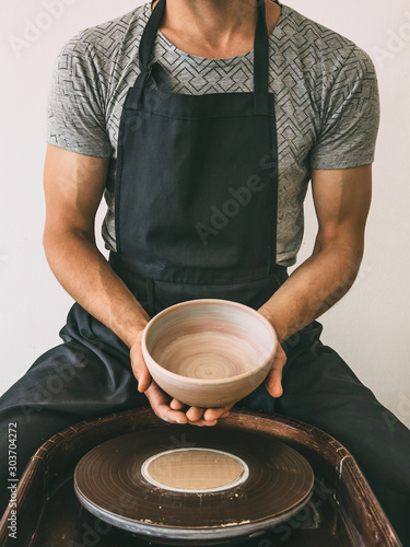 Ceramist at a pottery workshop A man holds a bowl made on a potter's wheel