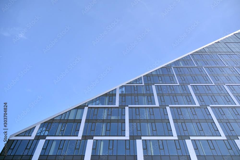 Modern office building wall made of steel and glass with blue sky Modern office building wall made of steel and glass with blue sky