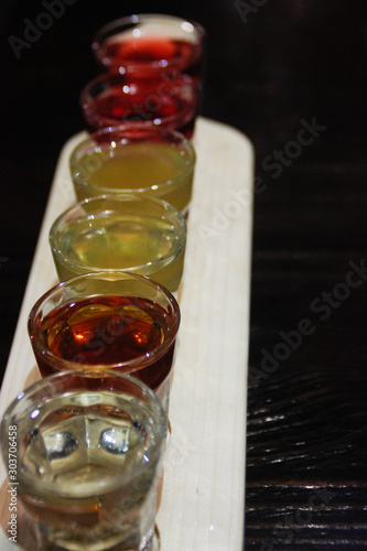 A set of shots with strong alcohol in small glass cups on a wooden tray on the table. National ukraiskih alkolol - liqueur on the berries.