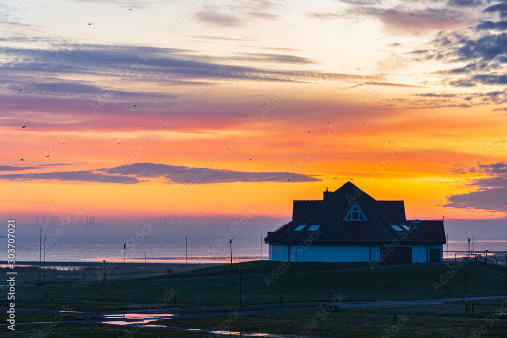 sunrise at the coast with a house sunrise morging clouds