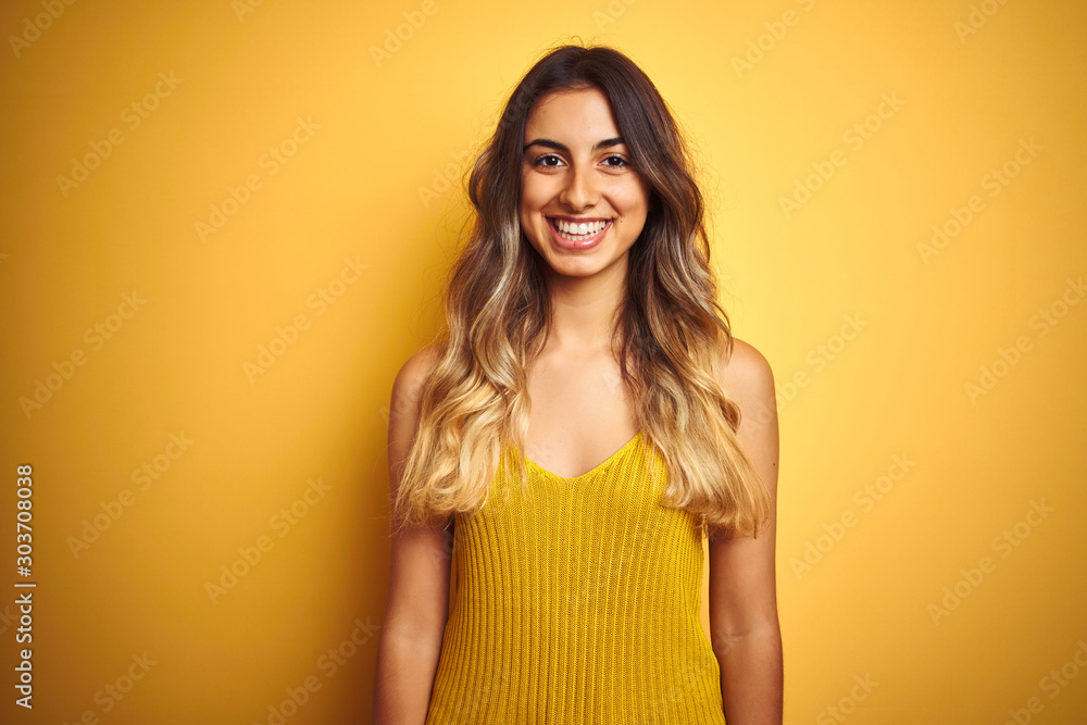 Young beautiful woman wearing t-shirt over yellow isolated background with a happy and cool smile on face. Lucky person. Young beautiful woman wearing t-shirt over yellow isolated background with a happy and cool smile on face. Lucky person.