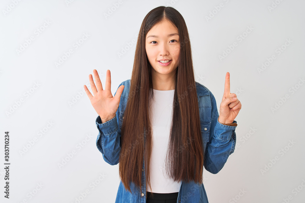 Young chinese woman wearing denim shirt standing over isolated white background showing and pointing up with fingers number six while smiling confident and happy. Young chinese woman wearing denim shirt standing over isolated white background showing and pointing up with fingers number six while smiling confident and happy.