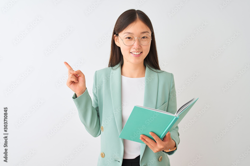 Young chinese student woman wearing glasses reading book over isolated white background very happy pointing with hand and finger to the side Young chinese student woman wearing glasses reading book over isolated white background very happy pointing with hand and finger to the side