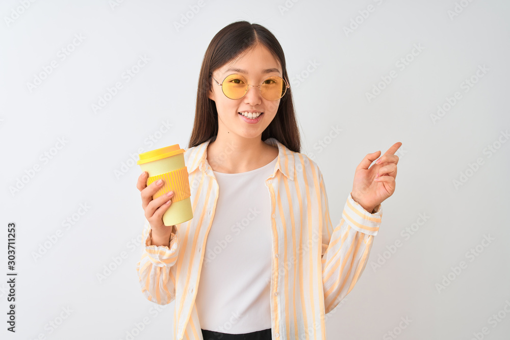 Young chinese woman wearing glasses drinking coffe over isolated white background very happy pointing with hand and finger to the side Young chinese woman wearing glasses drinking coffe over isolated white background very happy pointing with hand and finger to the side