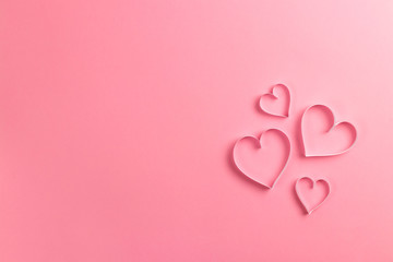 Composition for Valentine's Day February 14th. Delicate pink background and pink hearts cut out of paper. Greeting card. Flat lay, top view, copy space.