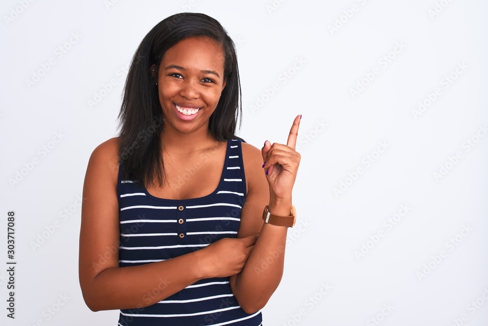 Beautiful young african american woman wearing summer t-shirt over isolated background with a big smile on face, pointing with hand and finger to the side looking at the camera. Beautiful young african american woman wearing summer t-shirt over isolated background with a big smile on face, pointing with hand and finger to the side looking at the camera.