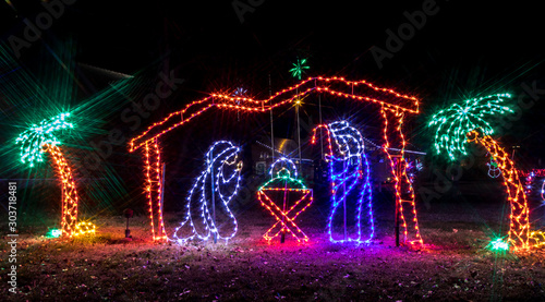 Colorful festive Holiday Christmas Light display of Nativity scene and palm trees