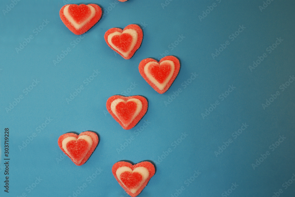 Marmalade sweets in sugar and in the shape of a heart on a bright background.