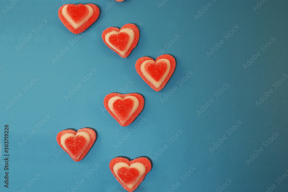 Obraz premium Marmalade sweets in sugar and in the shape of a heart on a bright background.
