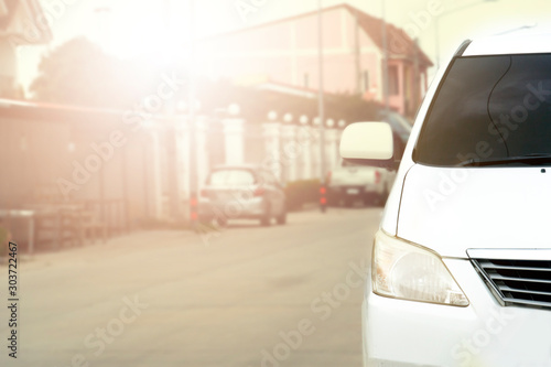 Front of white car on the road in the city of residence with sunset.