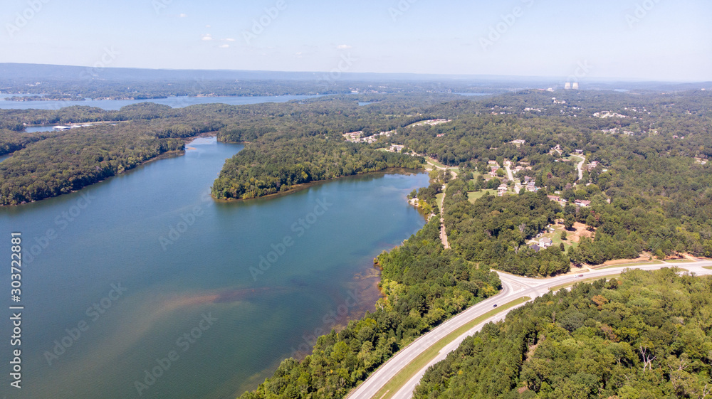 Aerial view of road between green summer forest and river