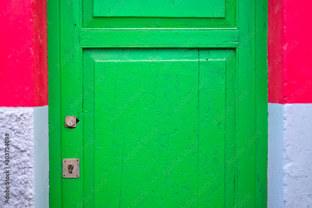 Bright green door (fragment) with two locks, gray and red wall on margins, abstract vividly painted architecture detail.
