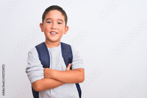 Beautiful student kid boy wearing backpack standing over isolated white background happy face smiling with crossed arms looking at the camera. Positive person. photo