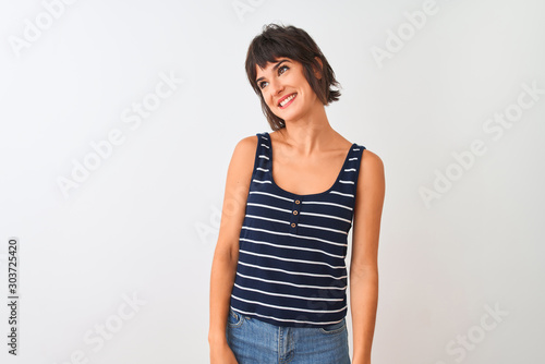 Young beautiful woman wearing striped t-shirt standing over isolated white background looking away to side with smile on face, natural expression. Laughing confident.