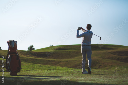 Back view, Asian Man hiting golf ball on the golf course in summer. sport, golfer concept.