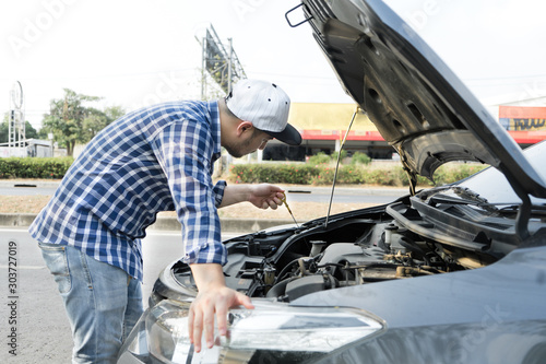 Man checking enginr lube oil level under car hood, fix broken car on the street. photo