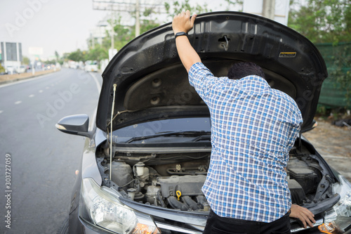mechanic wearing gloves open car hood checking car engine oil on the road after car breakdown problem.