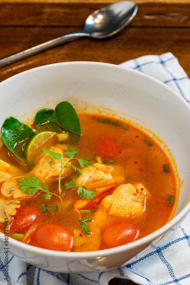 Chicken spicy soup with tomato and lemon in white bowl on wooden table. Chicken spicy soup with tomato and lemon in white bowl on wooden table.
