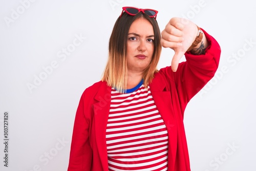 Young beautiful woman wearing striped t-shirt and jacket over isolated white background looking unhappy and angry showing rejection and negative with thumbs down gesture. Bad expression.