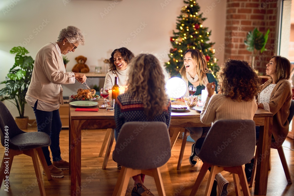 Obraz premium Beautiful group of women smiling happy and confident. Carving roasted turkey celebrating christmas at home