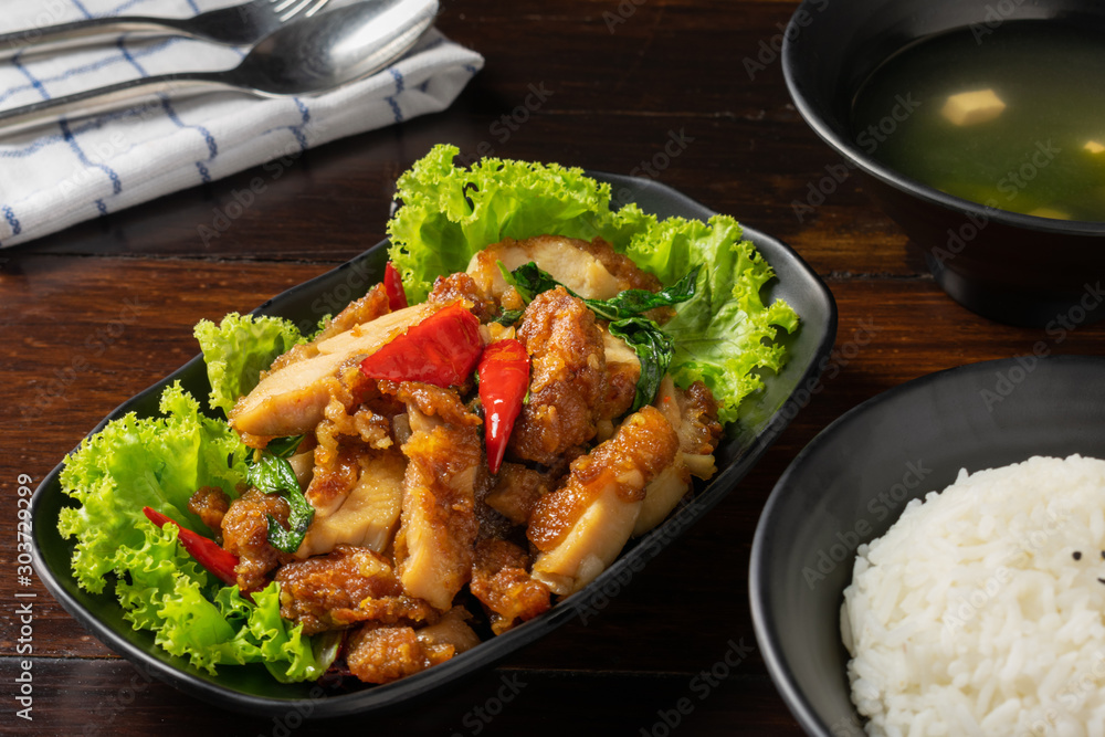 Fried basil with chicken in black dish with rice,salad and Miso soup on wooden table. Fried basil with chicken in black dish with rice,salad and Miso soup on wooden table.