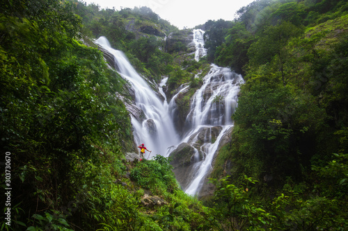 Fototapeta Naklejka Na Ścianę i Meble -  Young girl  hiking  on Pi-tu-gro waterfall, Beautiful waterfall in Tak  province, ThaiLand.