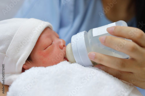 Photography little newborn baby sucking milk in bottle