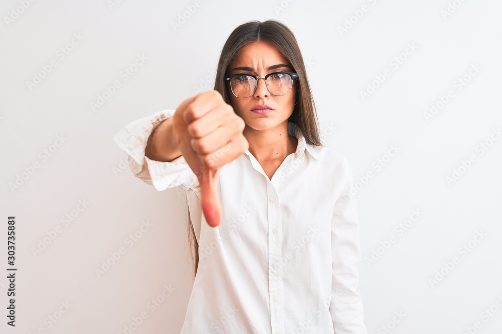 Young beautiful businesswoman wearing glasses standing over isolated white background looking unhappy and angry showing rejection and negative with thumbs down gesture. Bad expression. Young beautiful businesswoman wearing glasses standing over isolated white background looking unhappy and angry showing rejection and negative with thumbs down gesture. Bad expression.