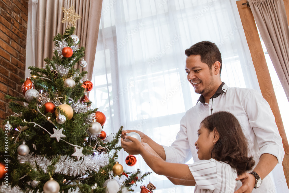 happy asian dad and girl decorating christmas tree together happy asian dad and girl decorating christmas tree together