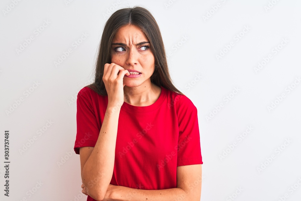 Young beautiful woman wearing red casual t-shirt standing over isolated white background looking stressed and nervous with hands on mouth biting nails. Anxiety problem. Young beautiful woman wearing red casual t-shirt standing over isolated white background looking stressed and nervous with hands on mouth biting nails. Anxiety problem.