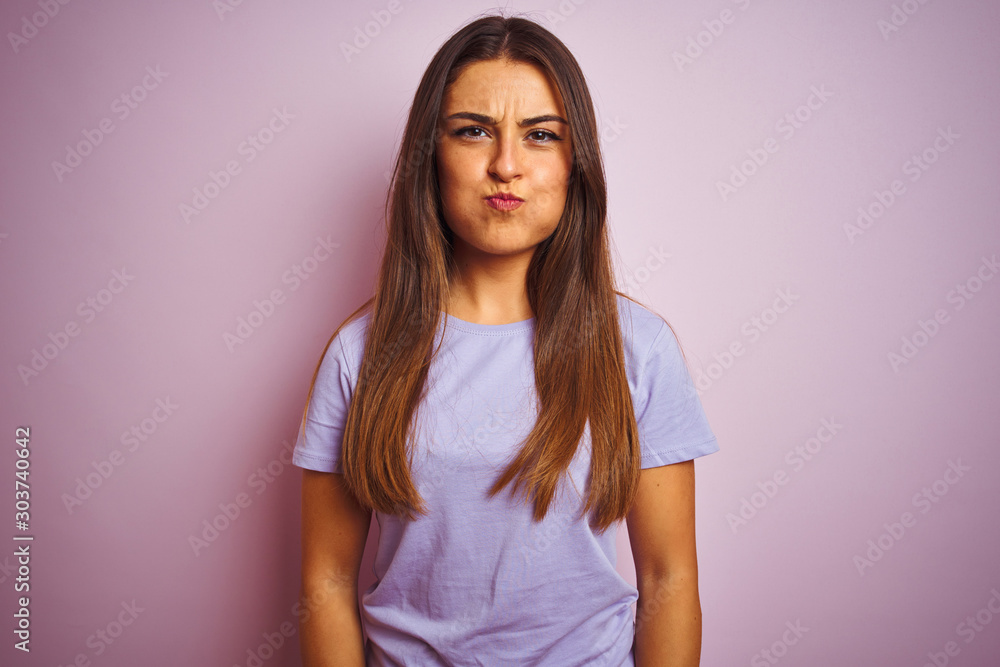 Young beautiful woman wearing casual t-shirt standing over isolated pink background puffing cheeks with funny face. Mouth inflated with air, crazy expression. Young beautiful woman wearing casual t-shirt standing over isolated pink background puffing cheeks with funny face. Mouth inflated with air, crazy expression.