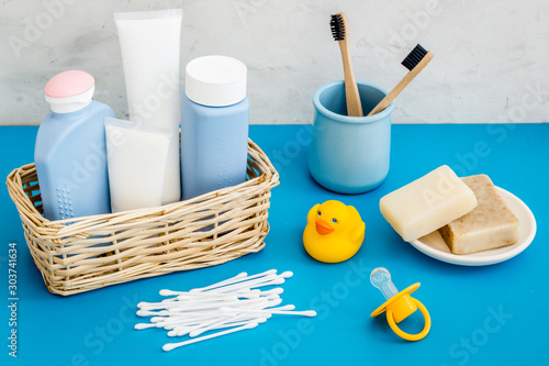 Baby bathroom cosmetics near pacifier and rubber duck on blue background