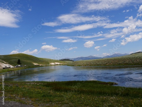 Wyoming, USA--July 2018: Medium wide shot of Yellowstone River with vehicles on the road on a bright beautiful day at Yellowstone National Park.