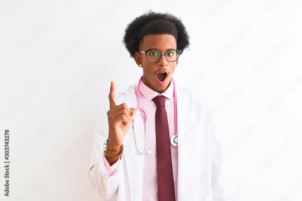 Young african american doctor man wearing pink stethoscope over isolated white background pointing finger up with successful idea. Exited and happy. Number one. Young african american doctor man wearing pink stethoscope over isolated white background pointing finger up with successful idea. Exited and happy. Number one.