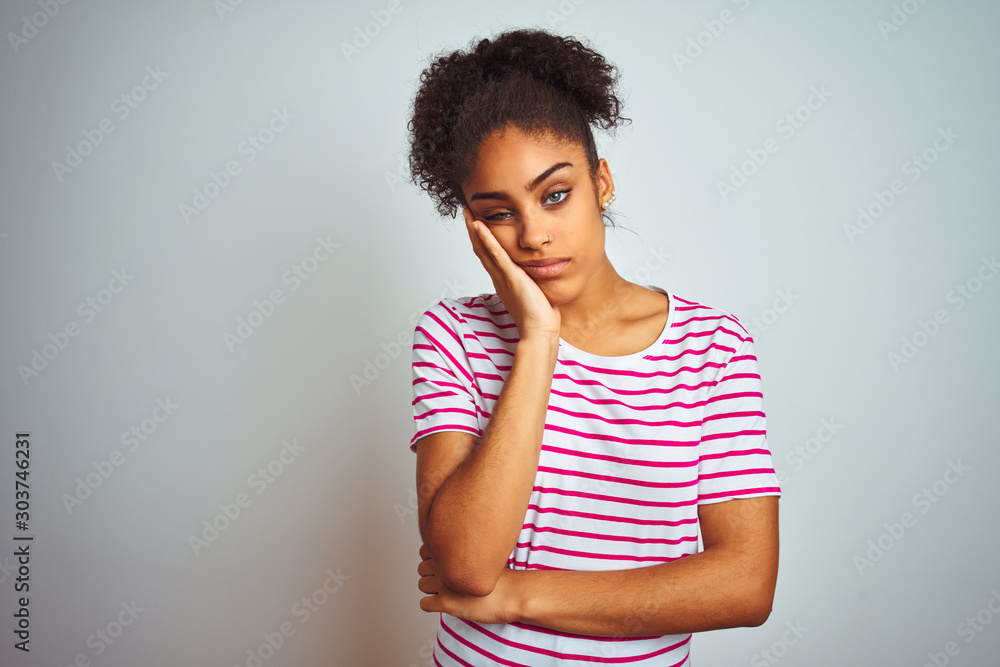 African american woman wearing casual pink striped t-shirt over isolated white background thinking looking tired and bored with depression problems with crossed arms. African american woman wearing casual pink striped t-shirt over isolated white background thinking looking tired and bored with depression problems with crossed arms.