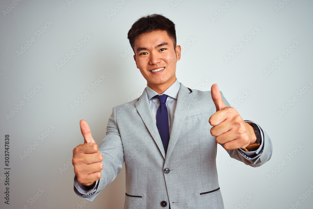 Φωτογραφία Asian chinese businessman wearing grey jacket and tie standing over isolated white background approving doing positive gesture with hand, thumbs up smiling and happy for success