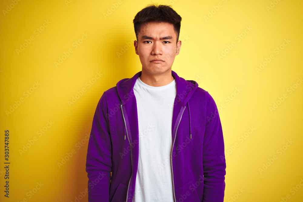 Φωτογραφία Young asian chinese man wearing purple sweatshirt standing over isolated yellow background depressed and worry for distress, crying angry and afraid