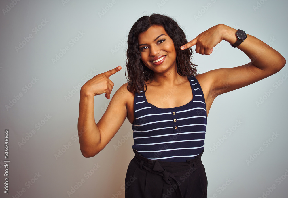 Fototapeta premium Transsexual transgender woman wearing striped t-shirt over isolated white background smiling cheerful showing and pointing with fingers teeth and mouth. Dental health concept.
