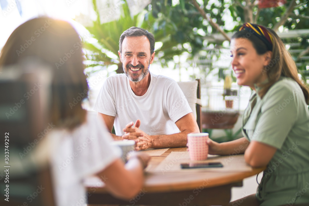 Beautiful family sitting on terrace drinking cup of coffee speaking and smiling Beautiful family sitting on terrace drinking cup of coffee speaking and smiling
