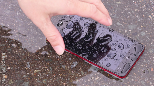 Fototapeta 雨に濡れたスマホを拾う