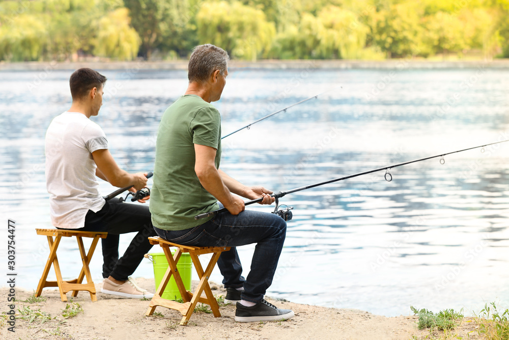 Young man and his father fishing on river Young man and his father fishing on river