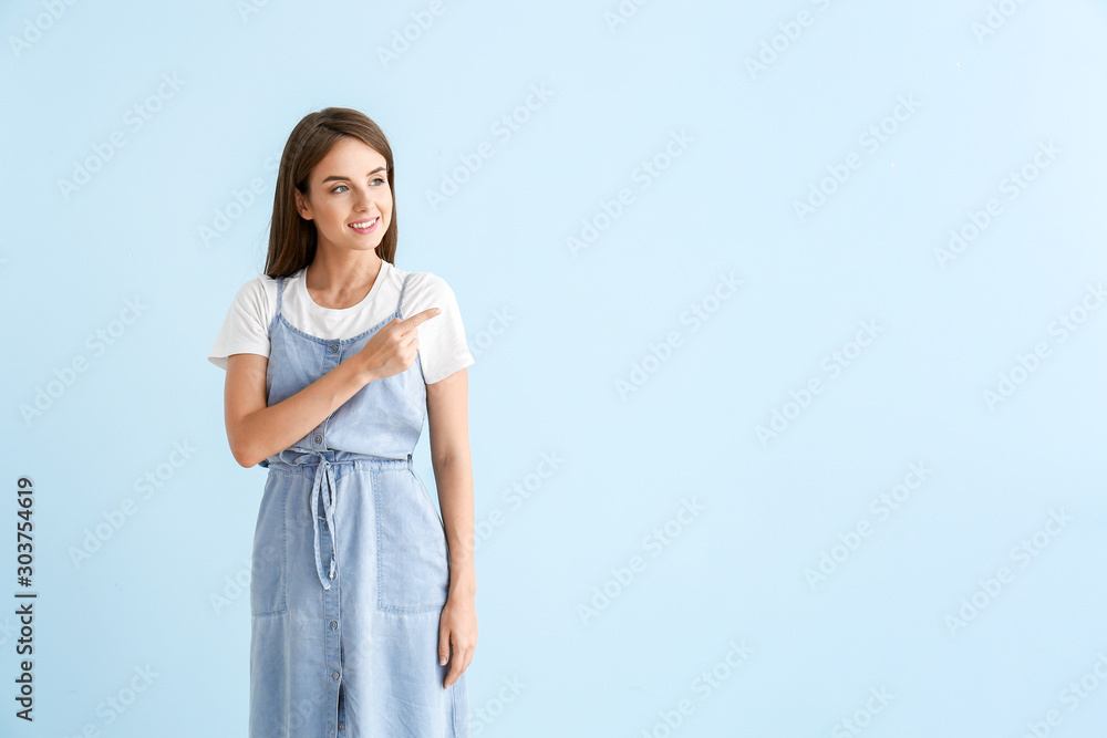 Beautiful young woman showing something on color background Beautiful young woman showing something on color background