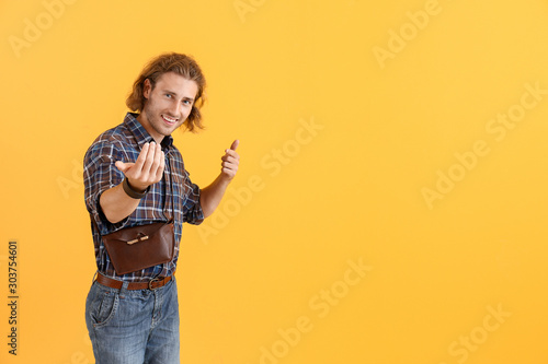 Handsome man showing "come here" gesture on color background