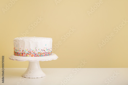 Tasty Birthday cake on table against color background