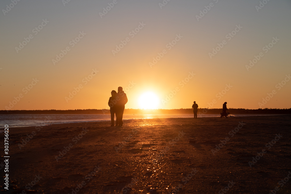 People scattered on beach at sunset 